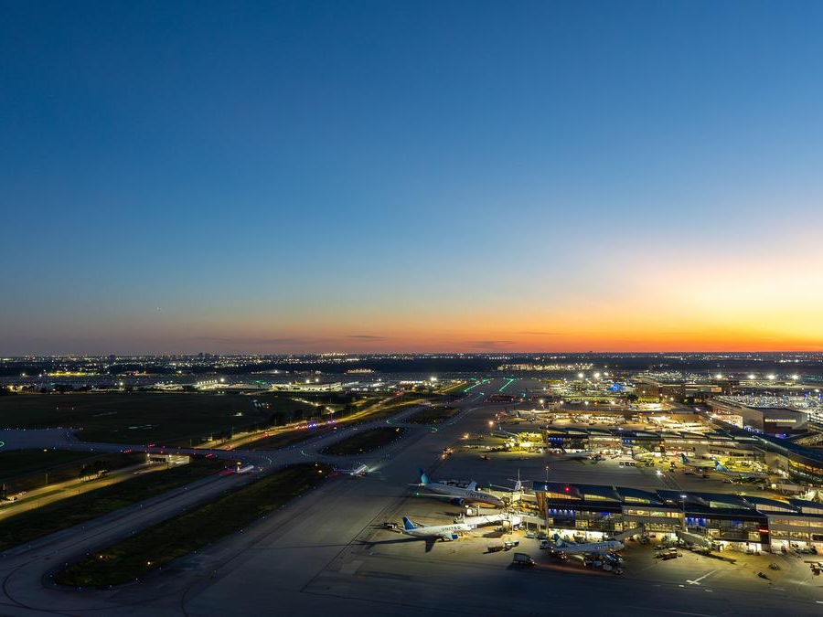 Aerial view of an airport at sunset, with softly lit runways and parked airplanes.