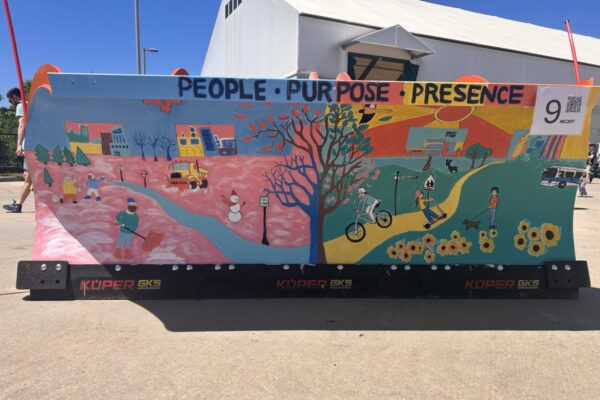 A snowplow painted with the words "People Purpose Presence," and city scenes.