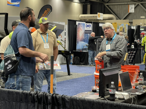 a photo of attendees and an exhibitor chatting on the Snow Conference exhibit floor