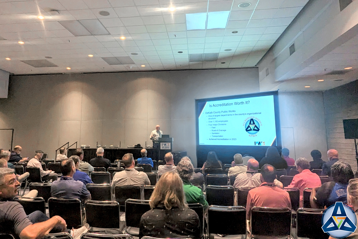People sit in a convention center room and listen to a speaker present on APWA Accreditation.