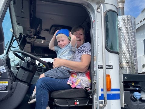 a child and an adult sit in the driver's seat of a truck